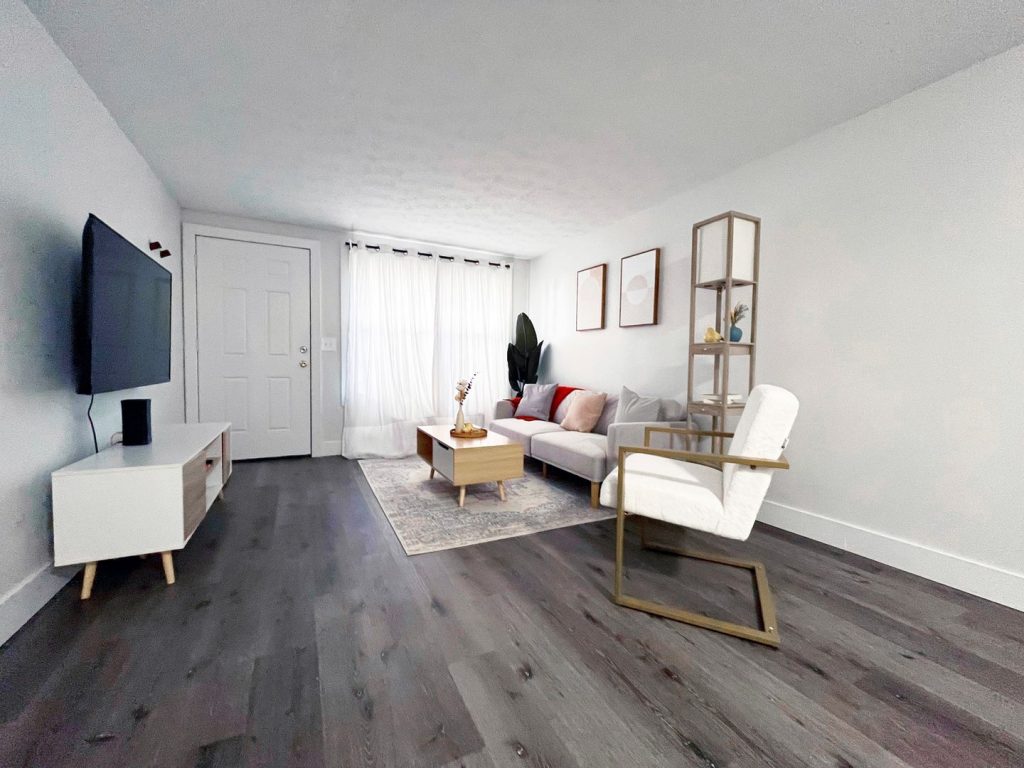 Woodgate Apartments, Johnstown, OH: living room with wall-mounted TV and front door